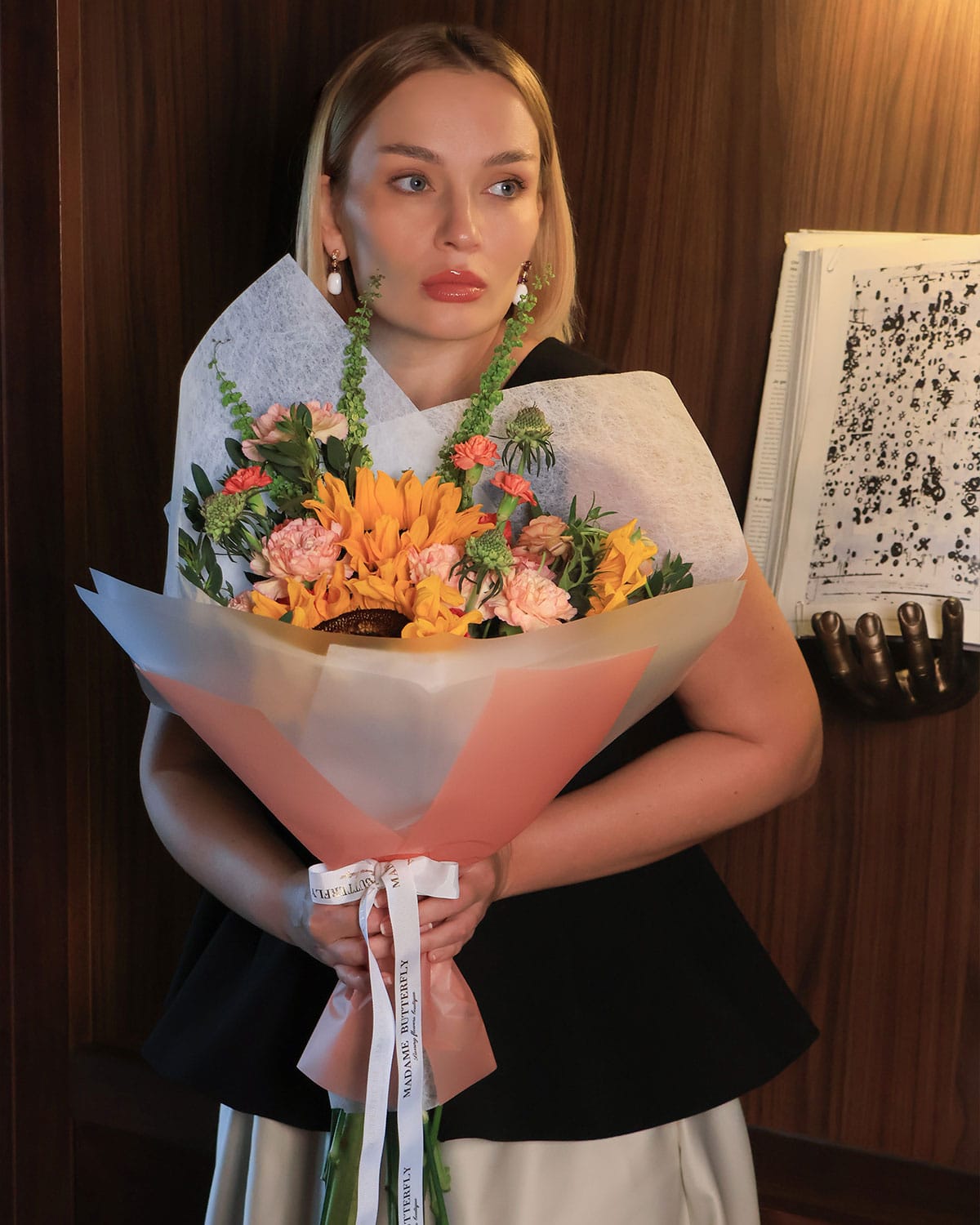 Una explosión de color y sofisticación, donde los girasoles, ranúnculos y claveles se combinan con scabiosas y rúmex en una envoltura blanca y naranja que resalta cada detalle. Este bouquet de Madame Butterfly representa alegría, lujo y creatividad.